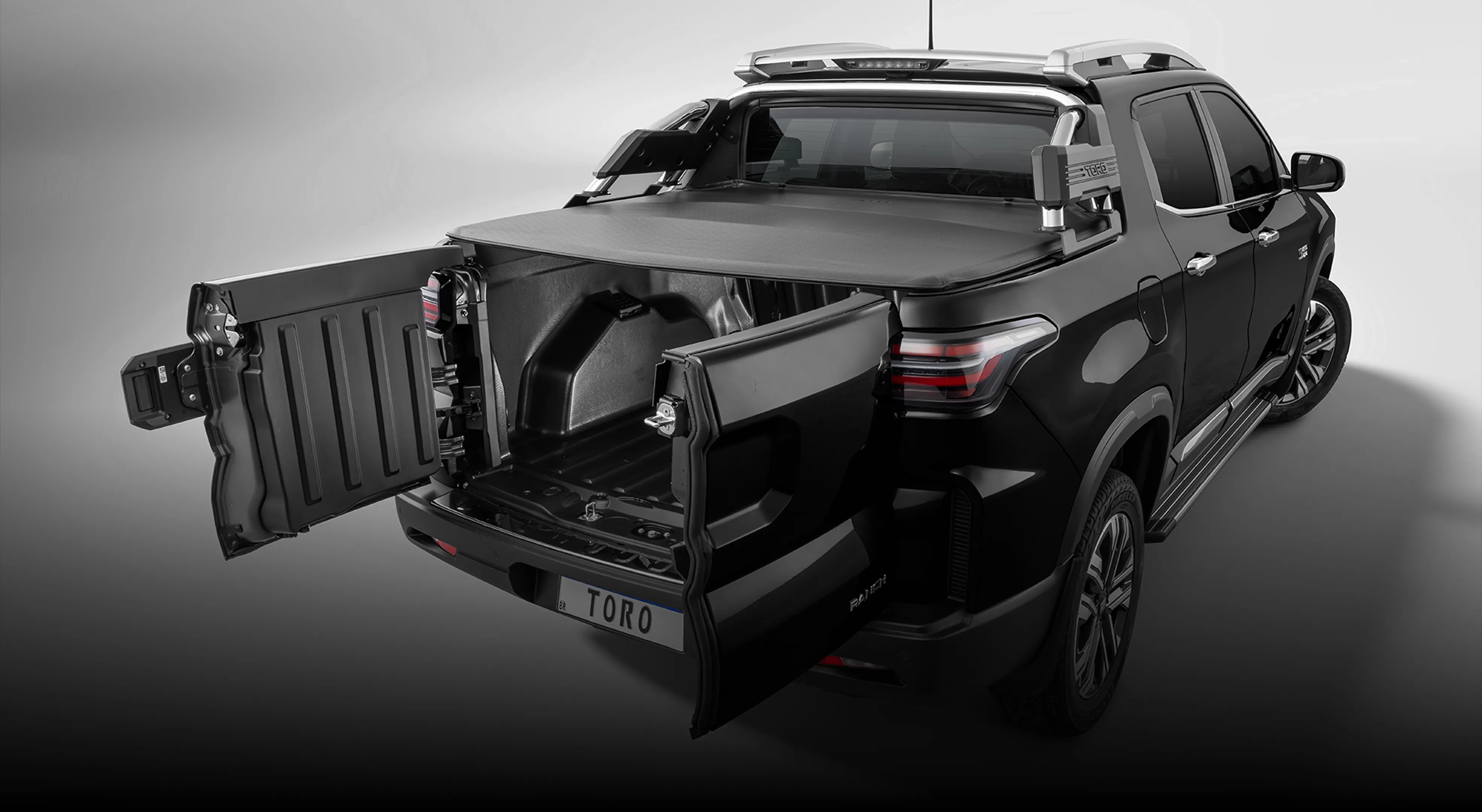 Fiat Toro preta com caçamba aberta, tampa bipartida articulada e revestimento interno.