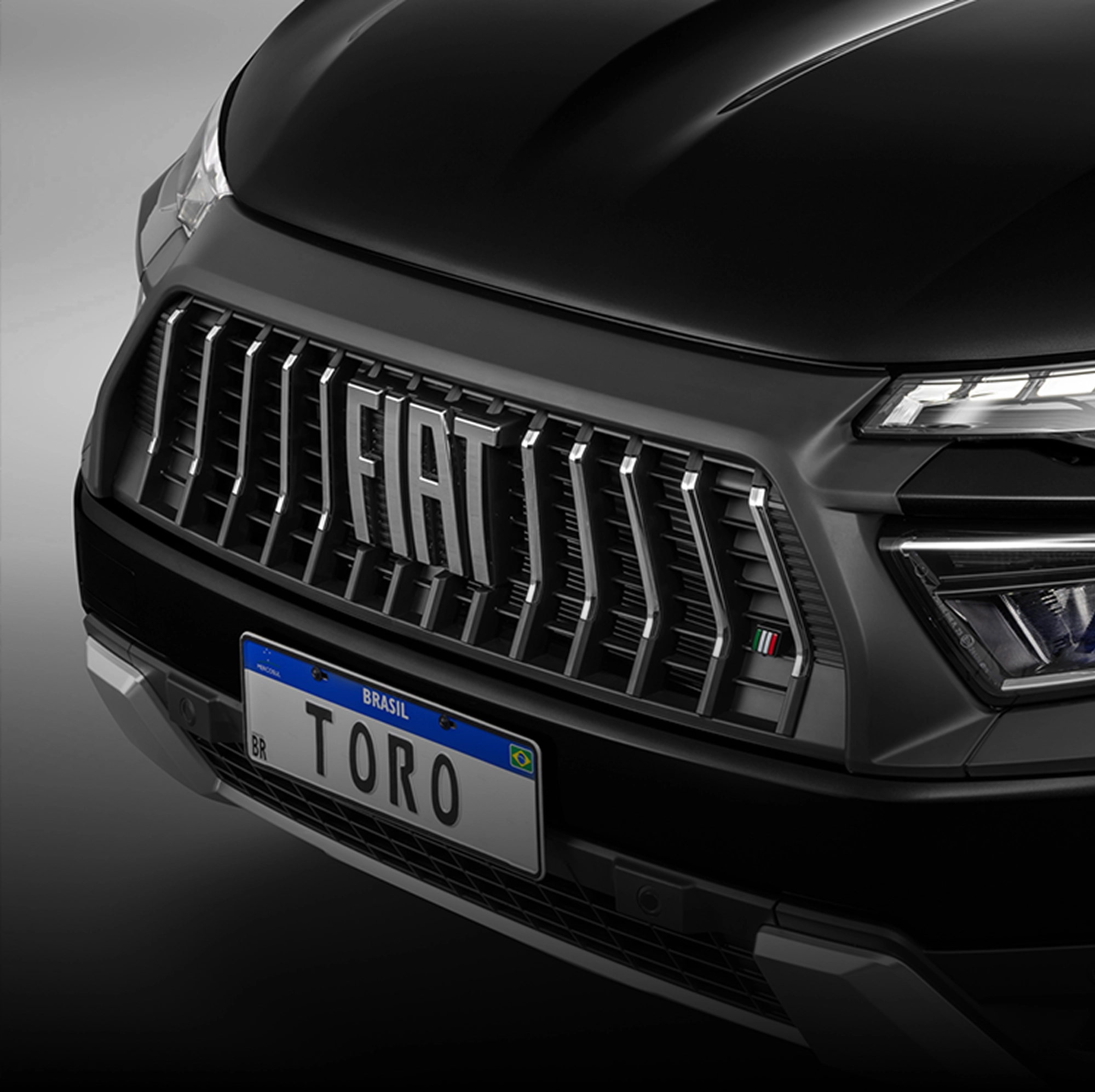 Fiat Toro preta com destaque para a grade frontal, faróis em LED acesos e logotipo Fiat centralizado.